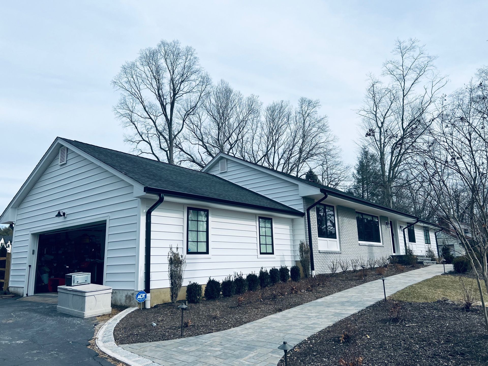 A white house with a garage and a walkway leading to it