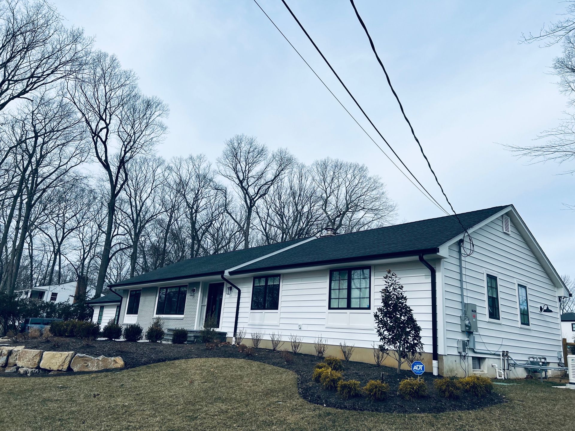 A white house with a green roof and trees in the background