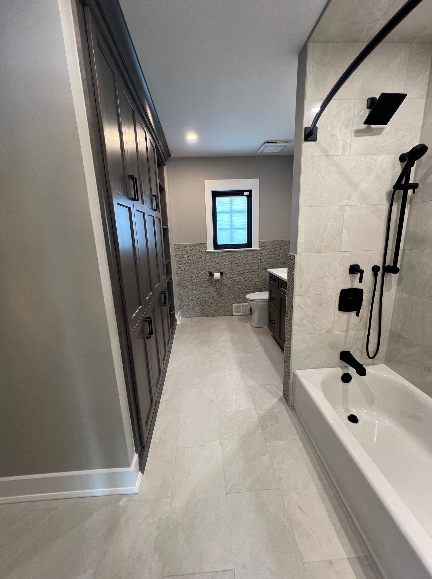 A bathroom with a tub, sink, toilet and window