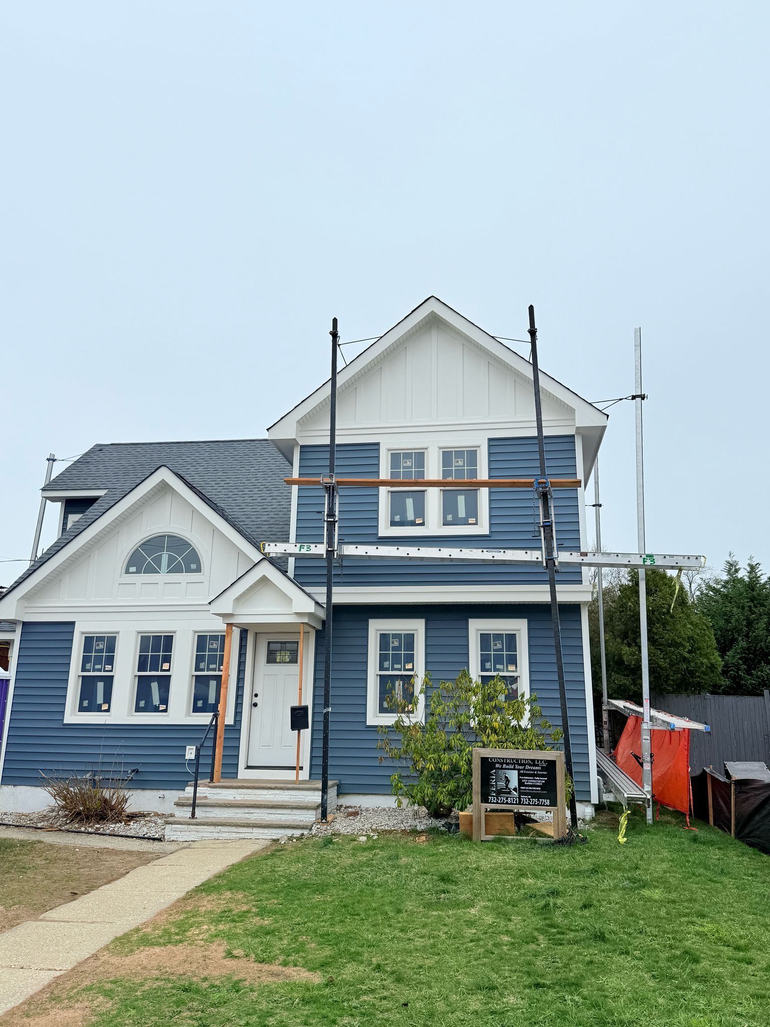 A blue and white house with scaffolding around it is being remodeled