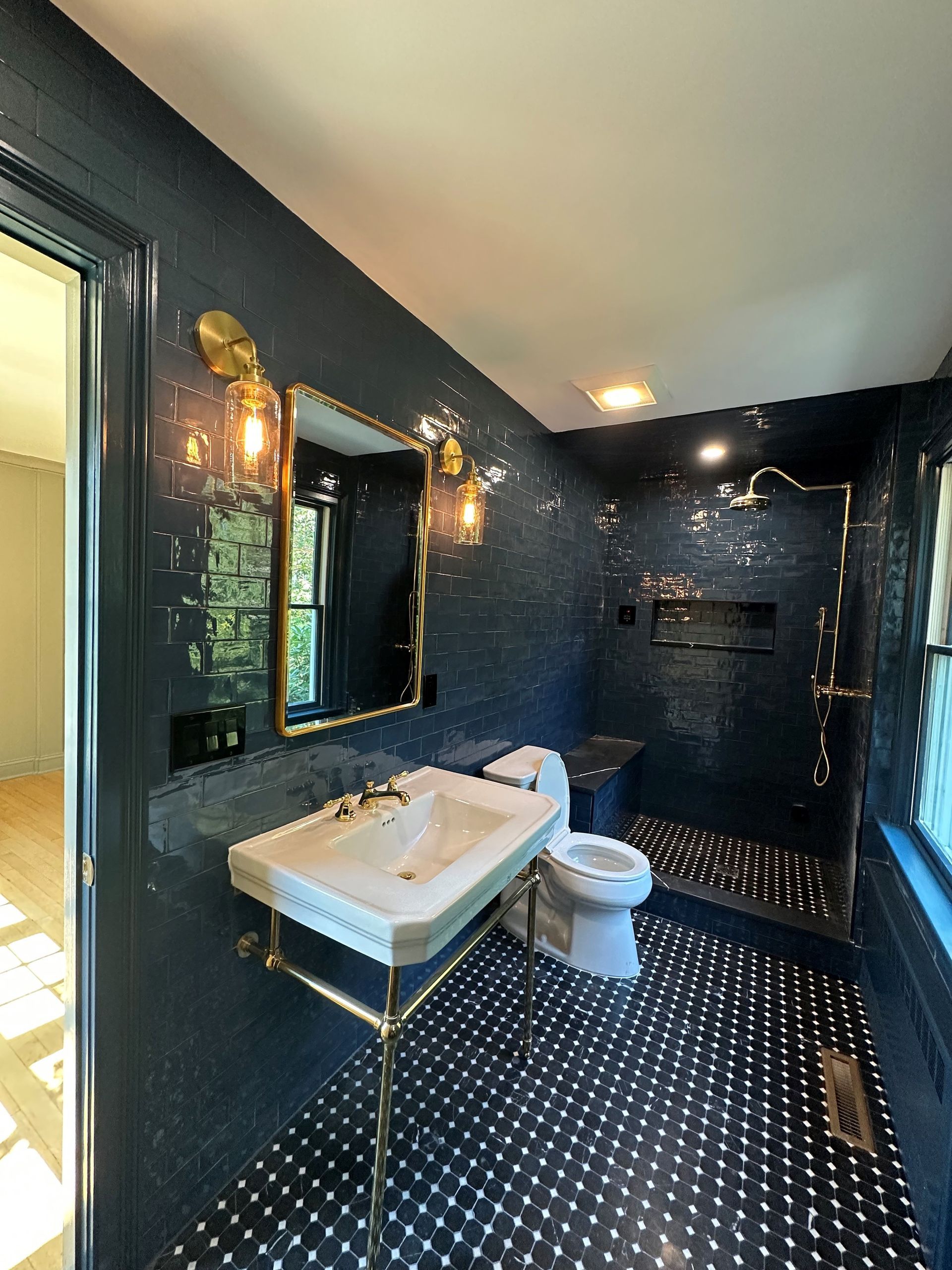 A bathroom with a sink , toilet , shower and mirror.