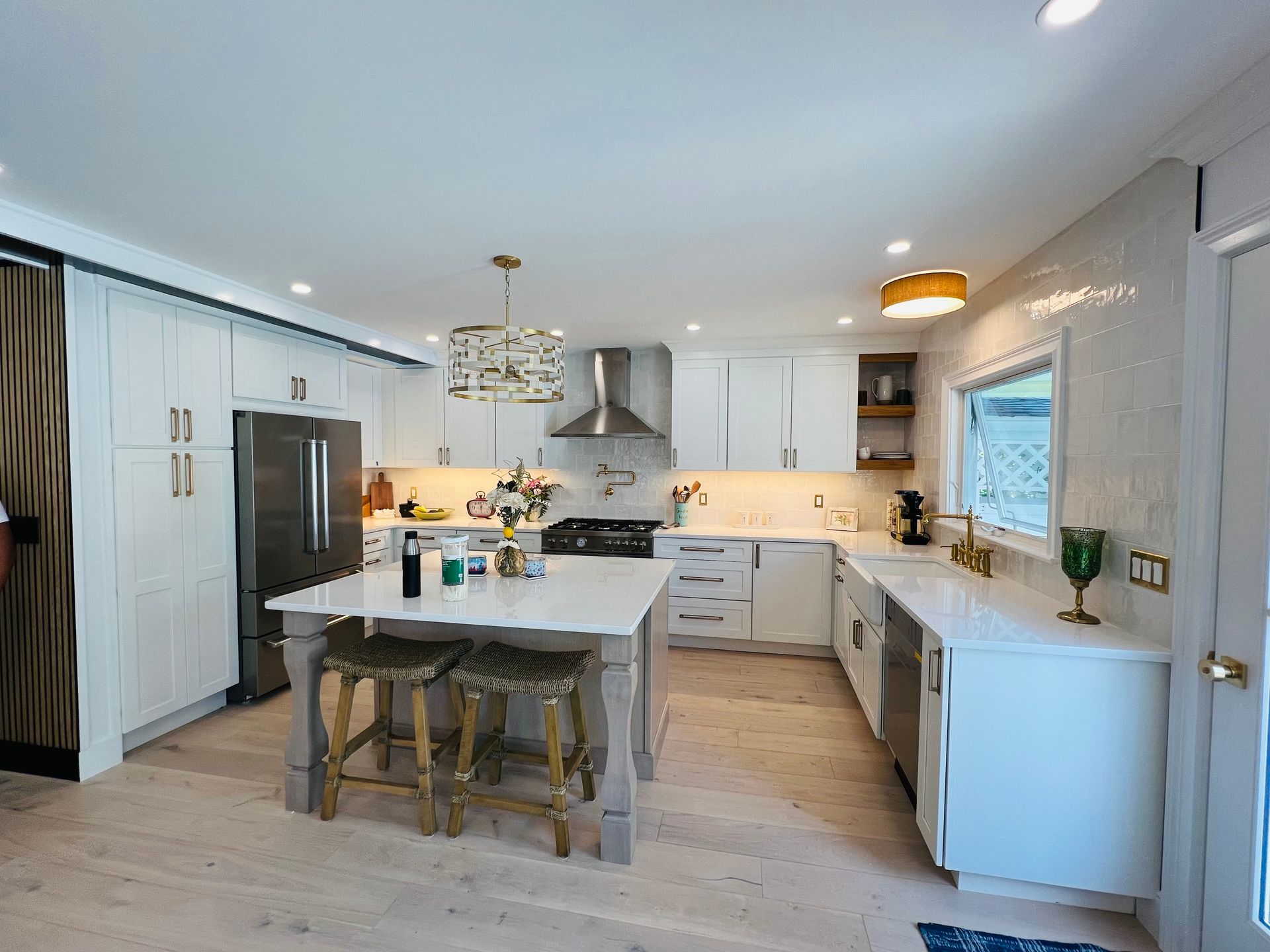 A kitchen with white cabinets , stainless steel appliances and a large island.