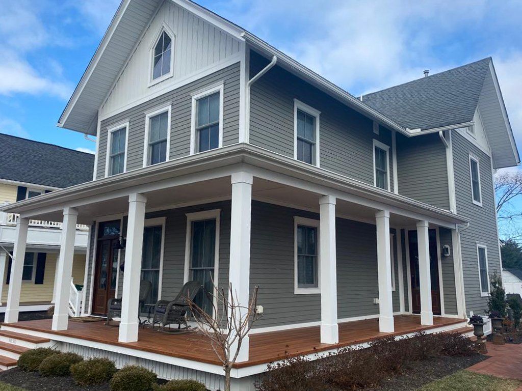 A large gray and white house with a large porch.