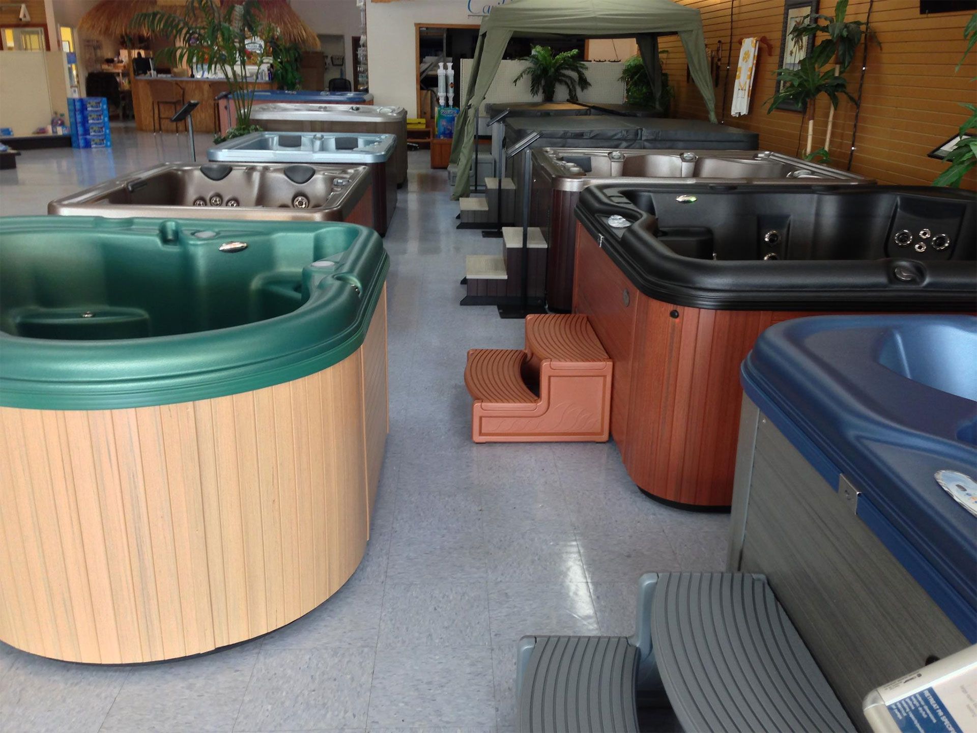 Several hot tubs on display in a store, different colors and styles, indoors.