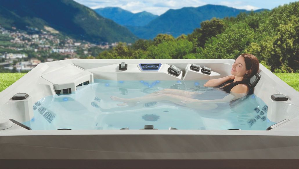 Woman relaxing in a hot tub outdoors with a scenic mountain view.