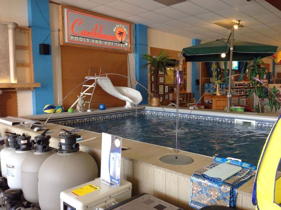 Indoor pool with slide, umbrella, and Caribbean pool and spa sign.
