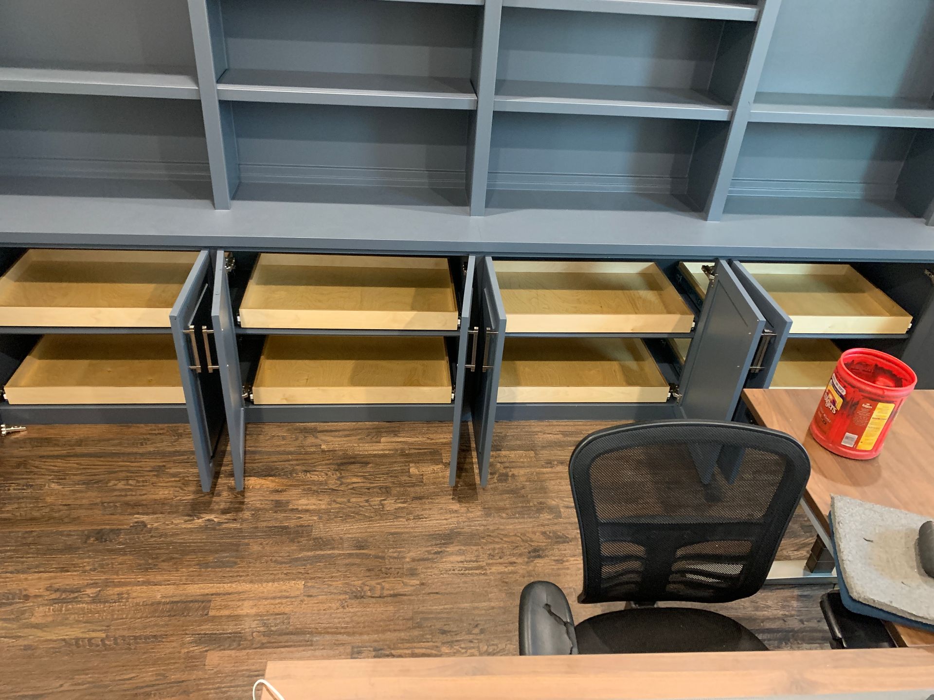 Gray built-in shelves with open drawers, near an office chair and desk.