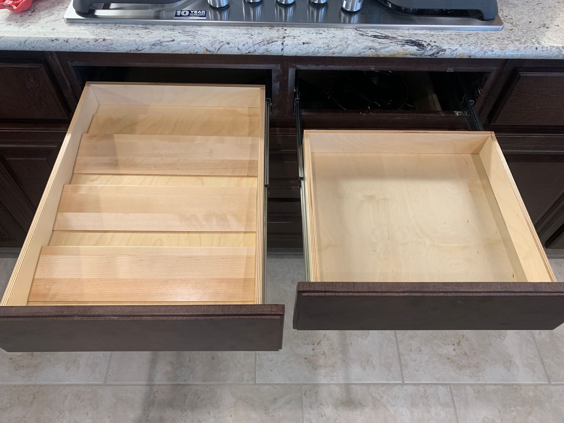 Two open kitchen drawers; one with tiered wooden spice rack, the other empty.
