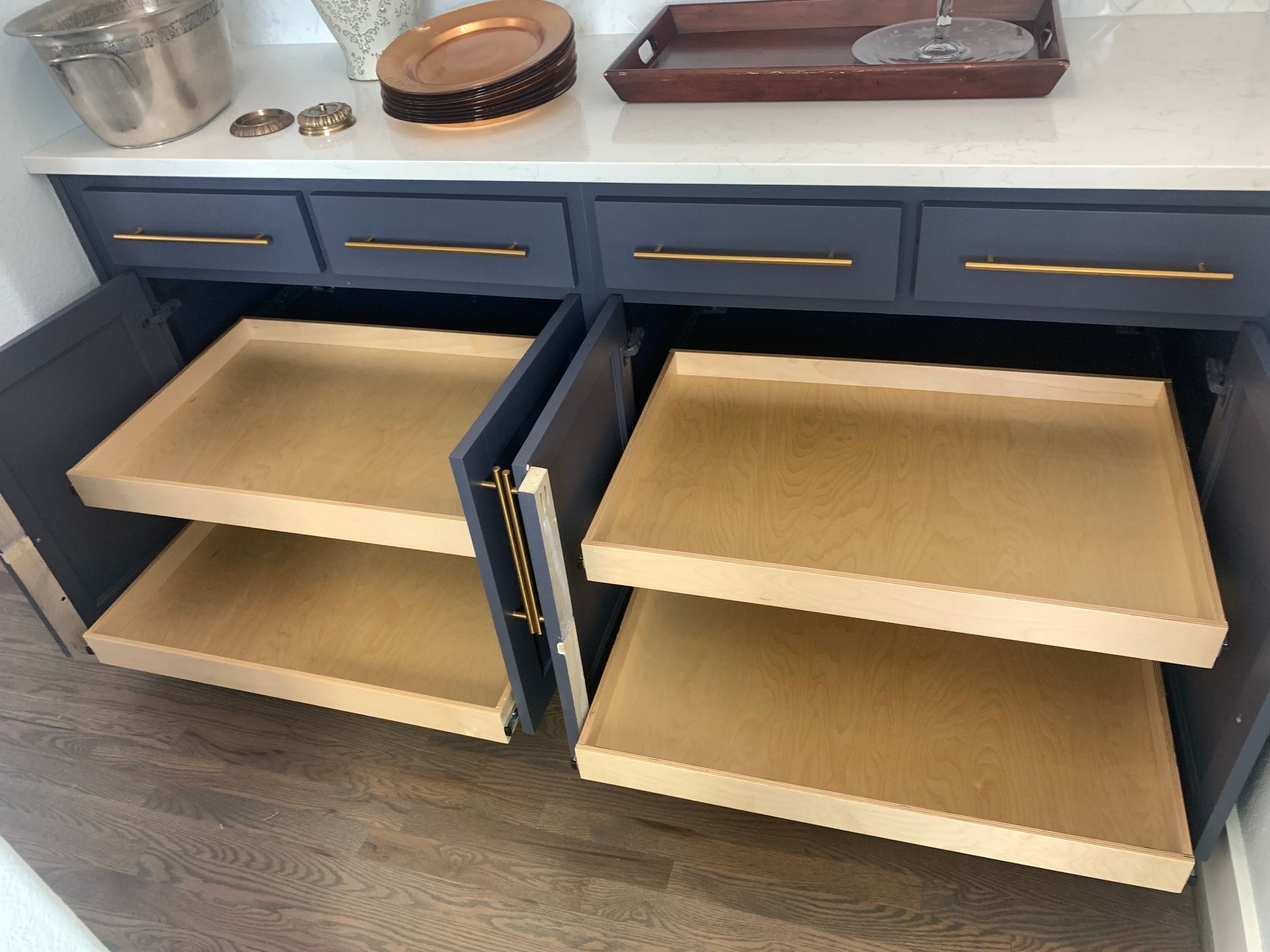 Dark blue cabinet with gold hardware; pull-out shelves in a kitchen.