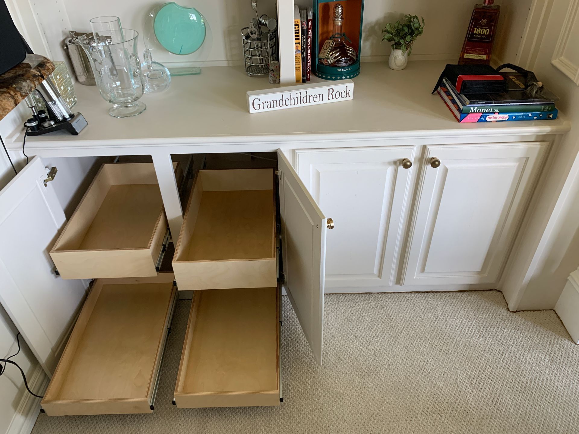 White cabinet with open drawers. Light tan drawers. White interior with decor on shelf above.