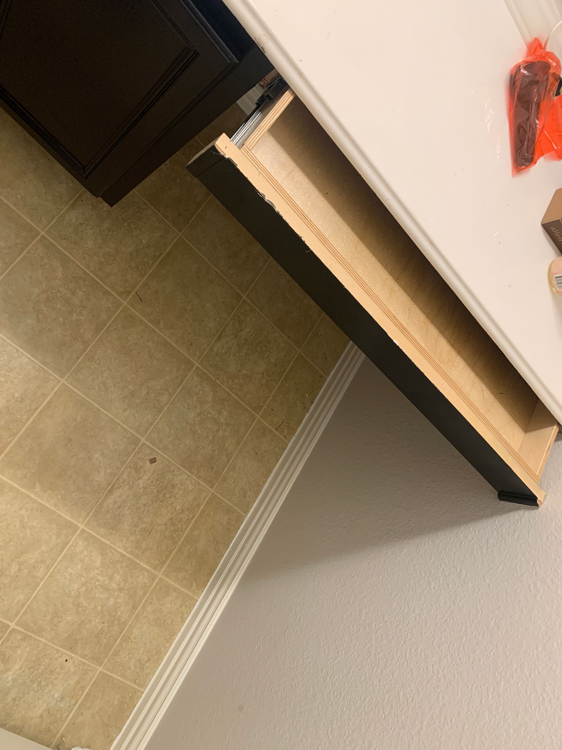 A drawer pulled open in a kitchen. The inside is wooden and empty.