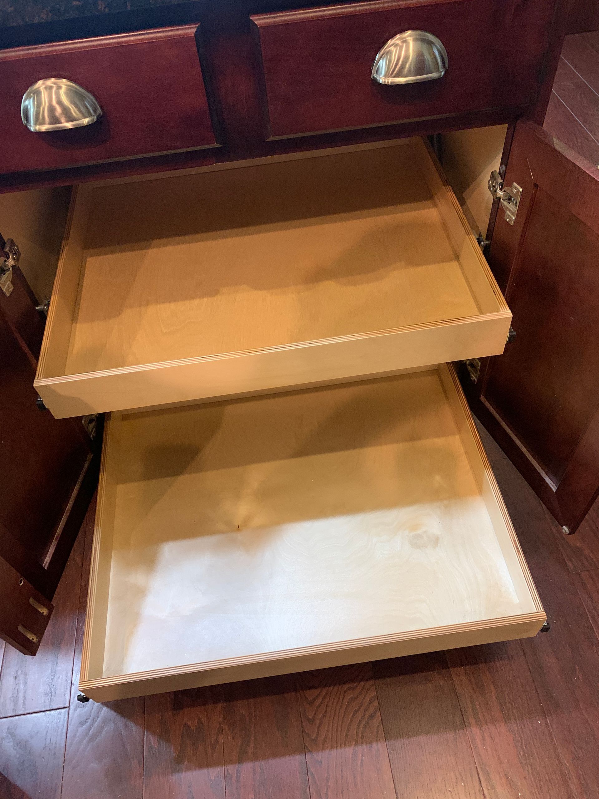 Wooden kitchen cabinet with two open drawers.