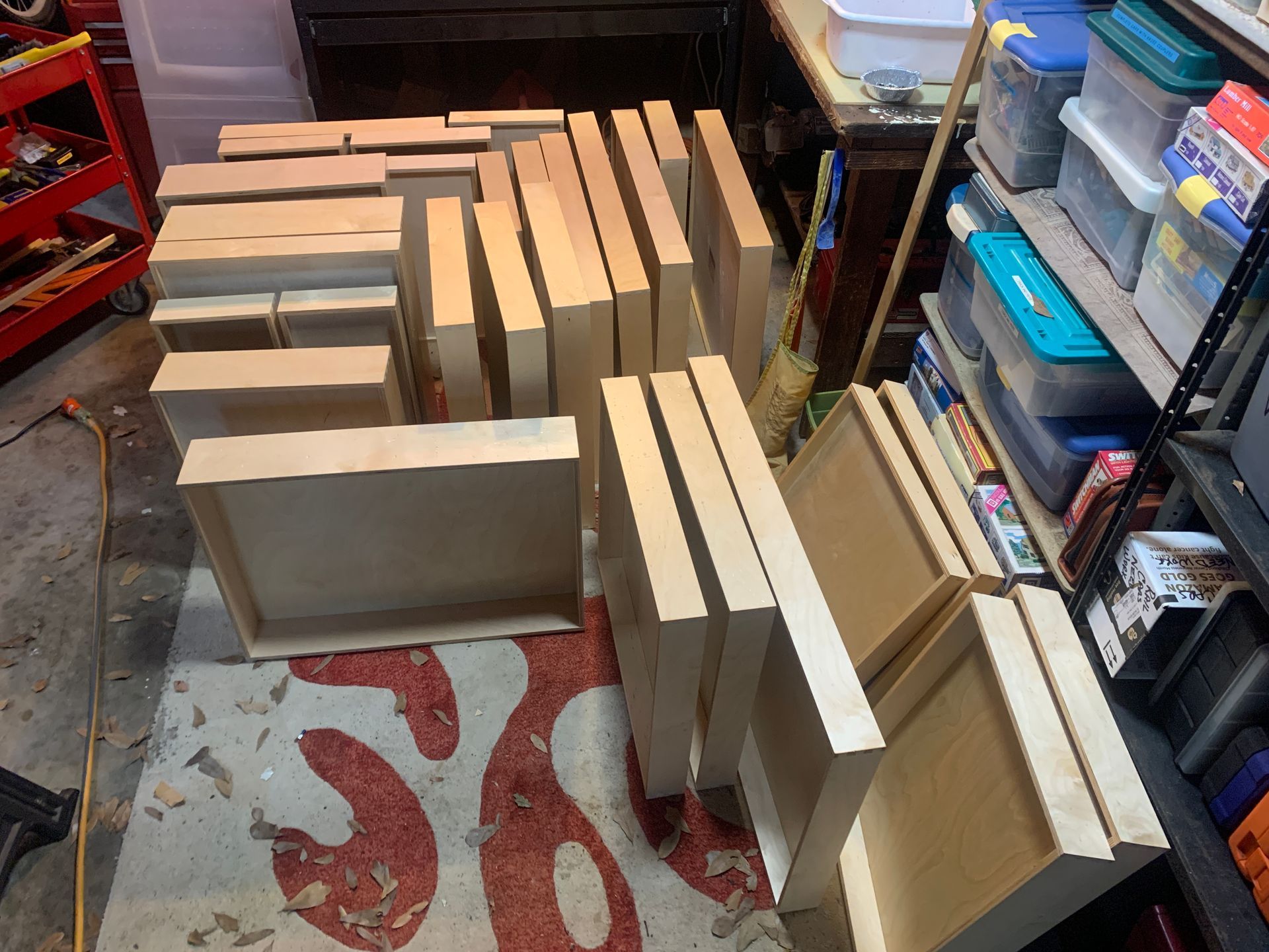 Wooden boxes and planks on a rug in a garage, surrounded by tools and storage containers.