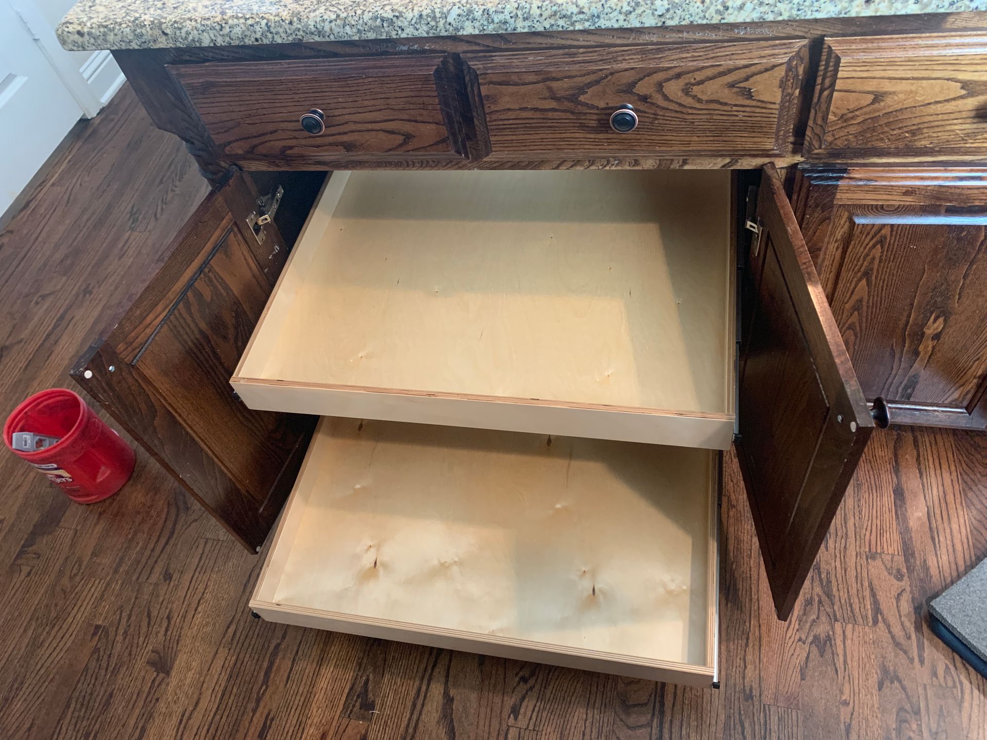 Cabinet with open drawers, wood grain finish, granite countertop.