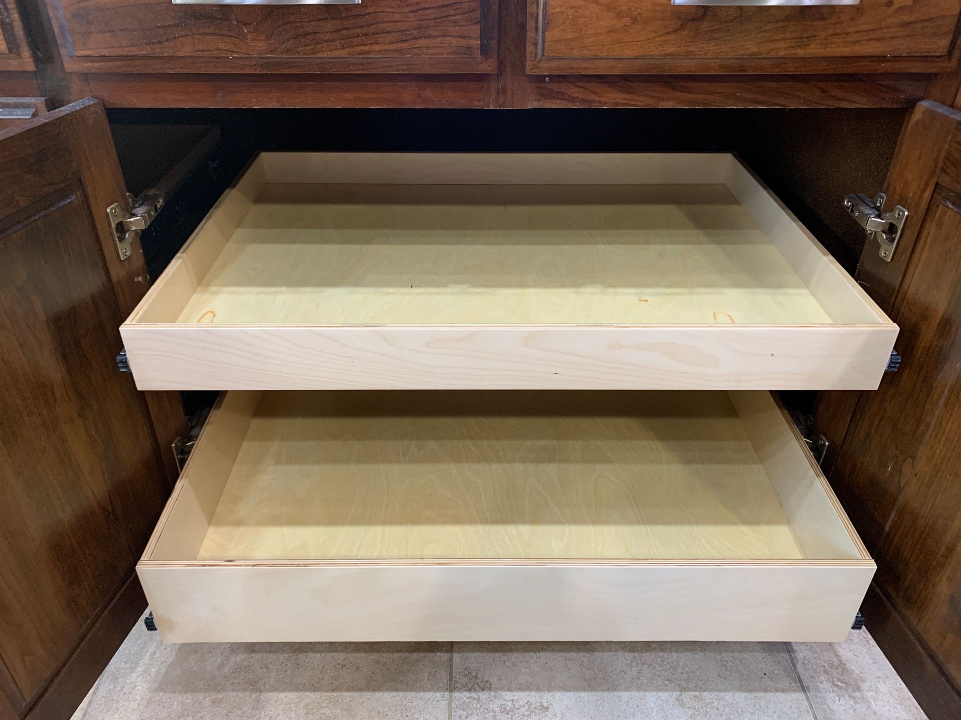 Two open, light-colored pull-out drawers inside a dark wood cabinet.
