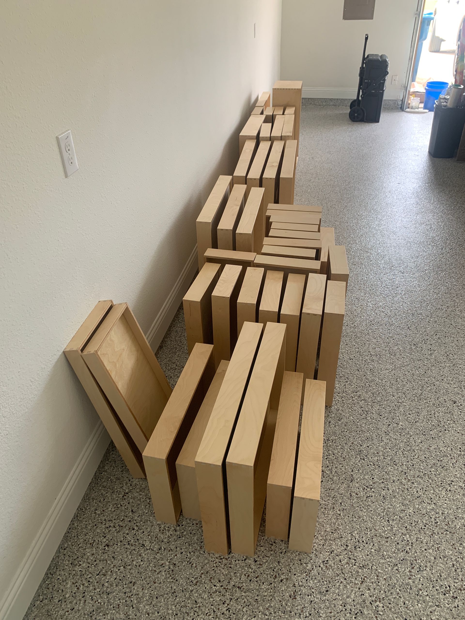 Wooden blocks stacked along a wall in a garage with a speckled floor.