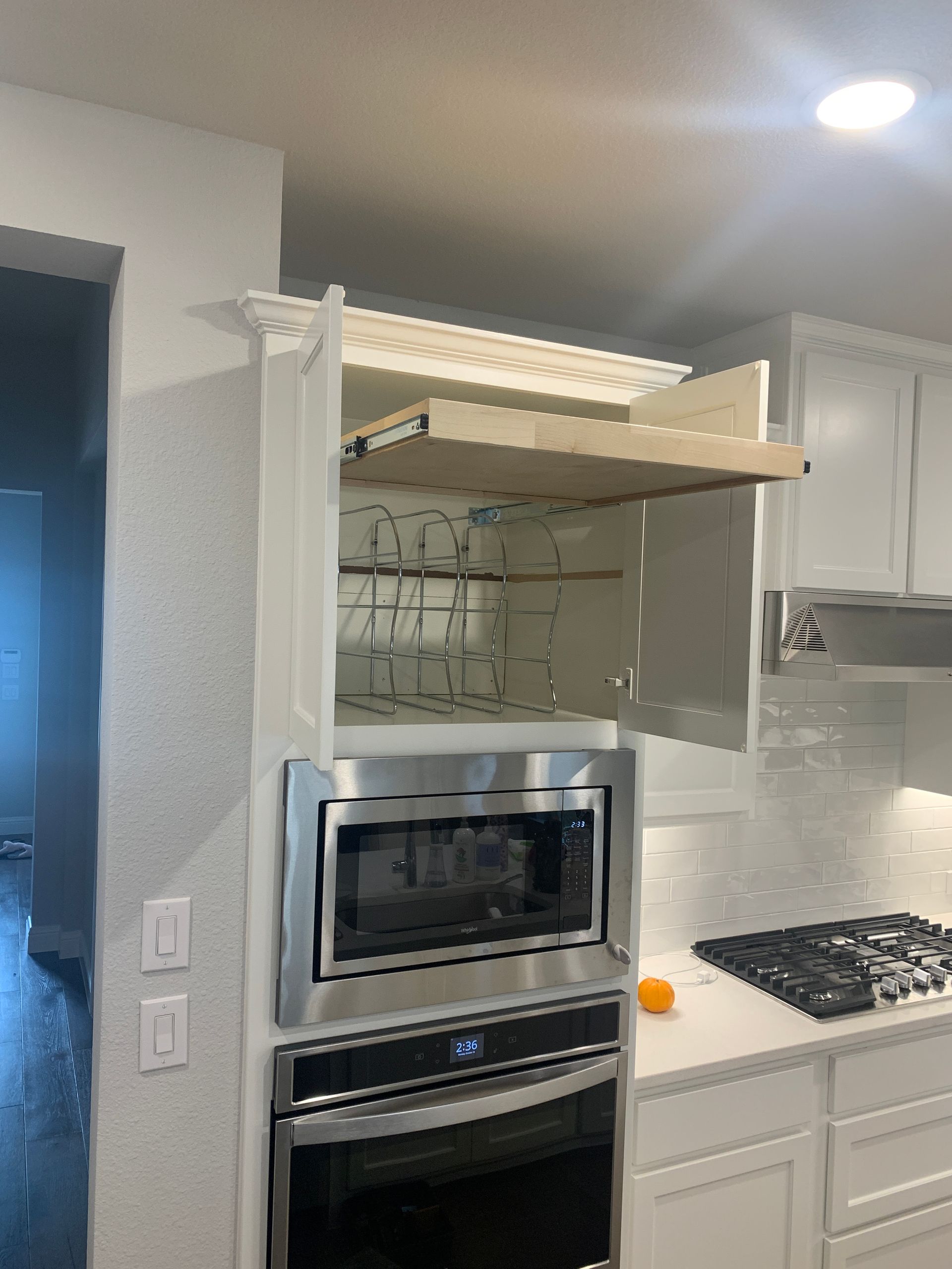White kitchen cabinet with microwave, oven, and drying rack.