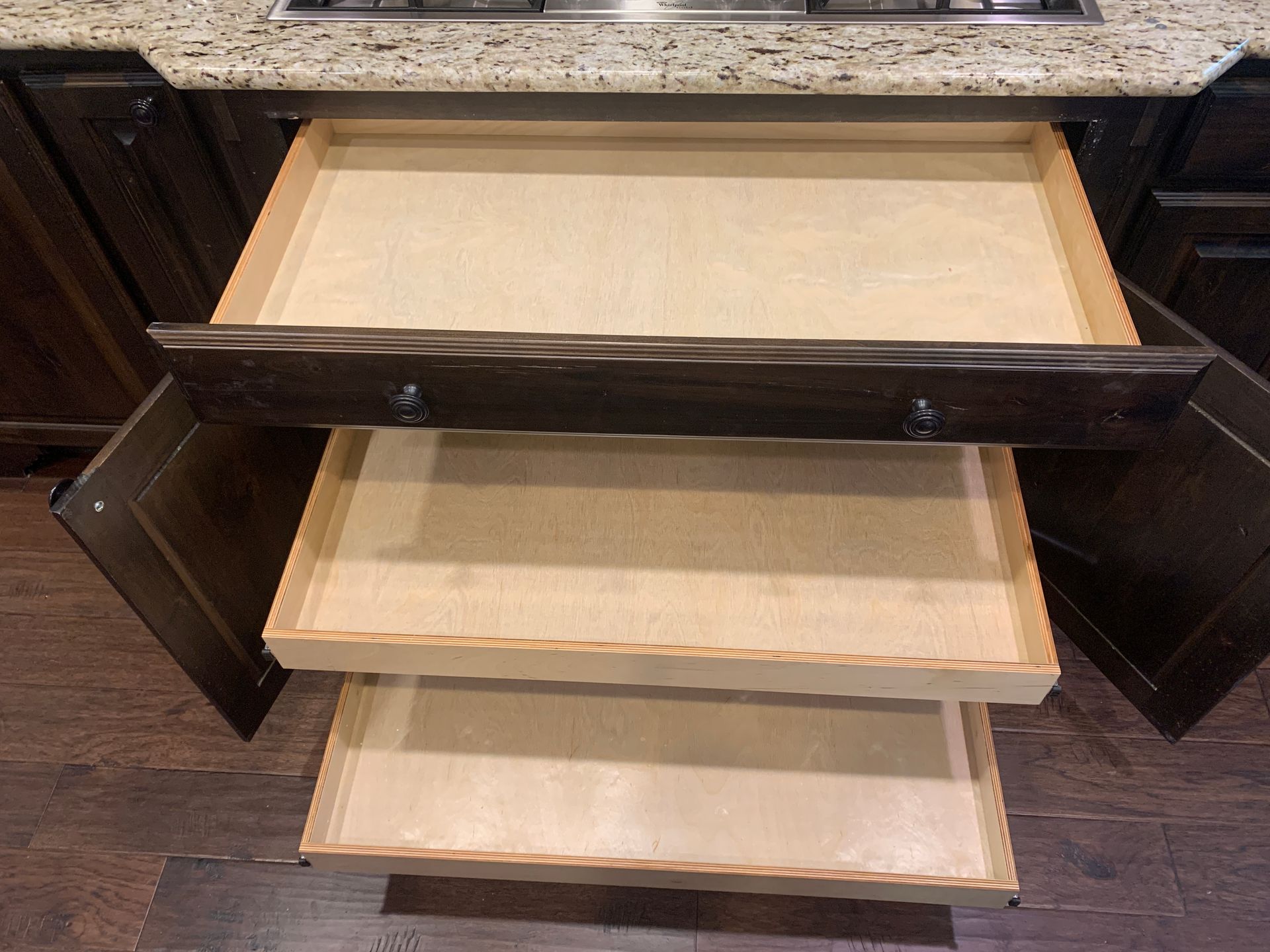Open kitchen drawers, dark wood cabinets, granite countertop.