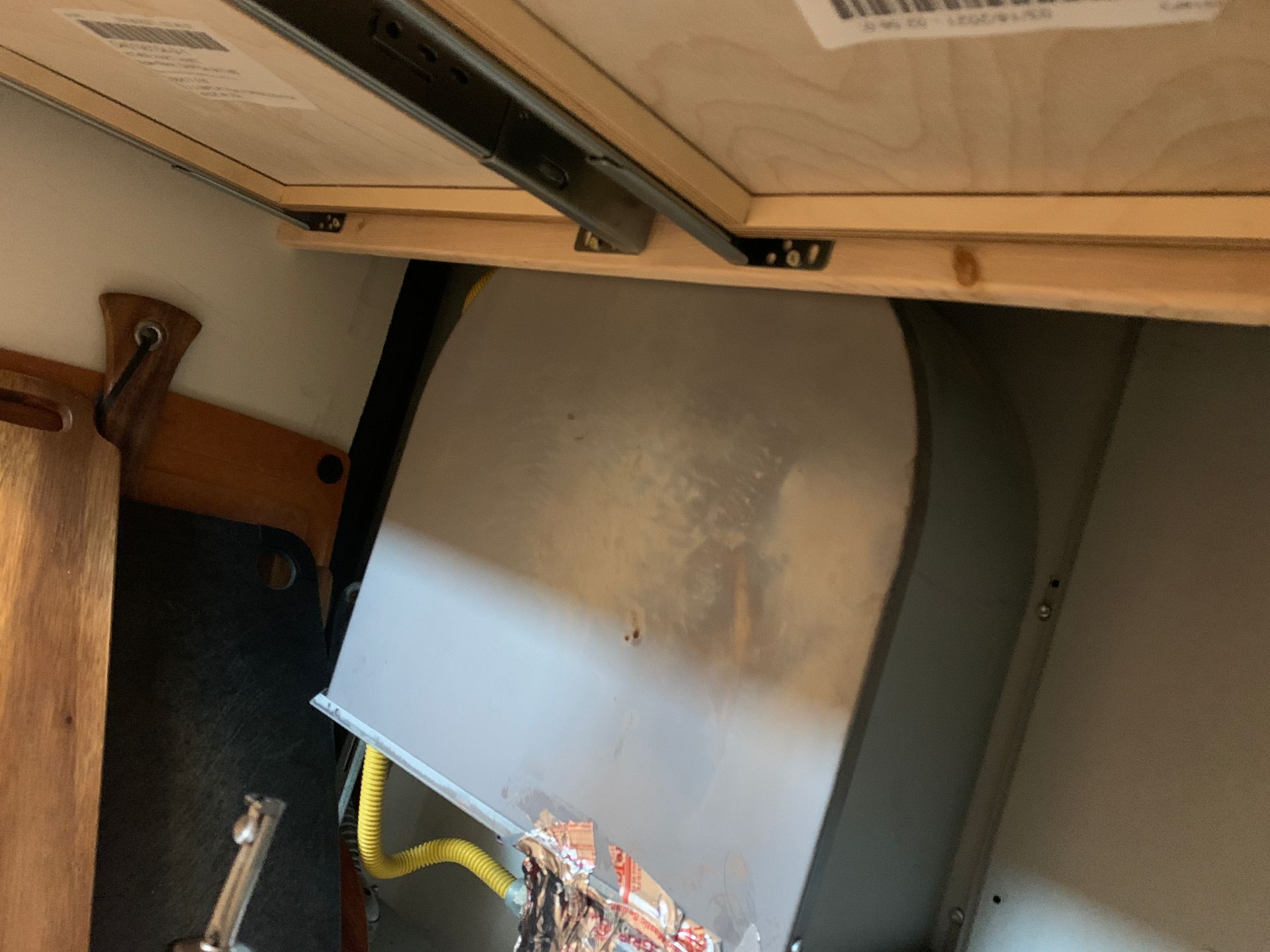 Metal box tucked under a wooden table. Yellow wires and electrical components are visible. Dark interior setting.