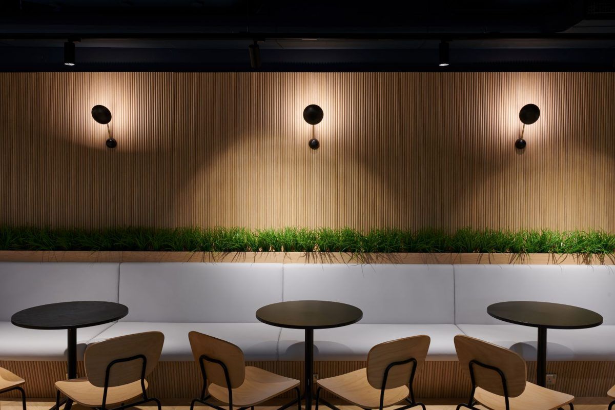 Cozy cafe seating with round tables, light wood paneling, and soft lighting.