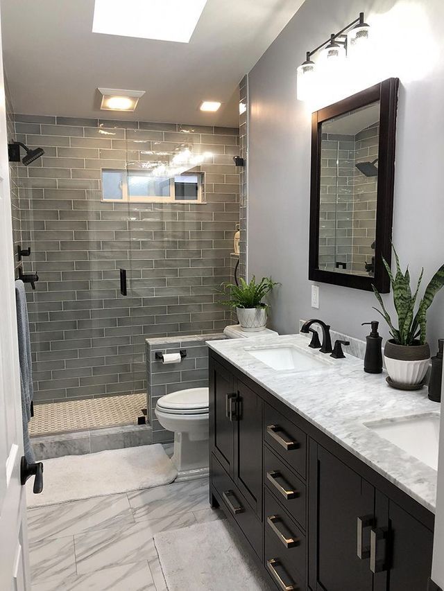 A bathroom with two sinks, a toilet, and a walk in shower.