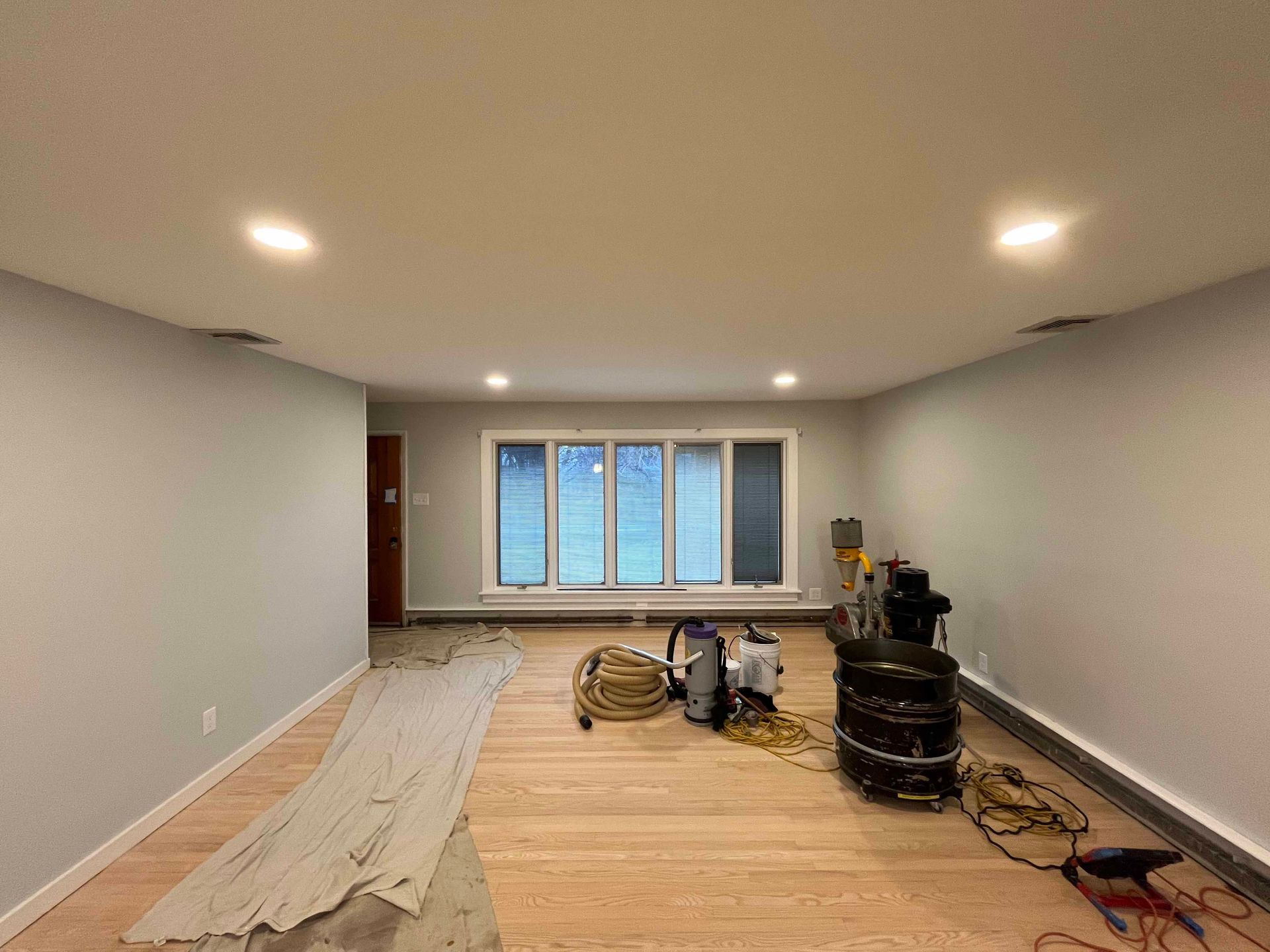 A large empty room with hardwood floors and a window.