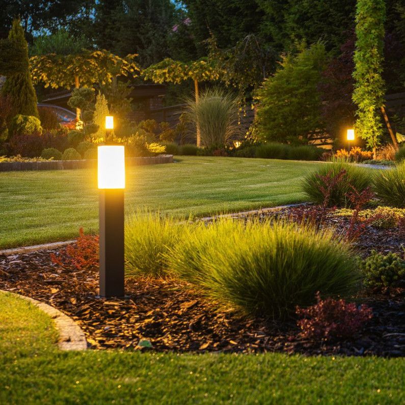 A garden with a light on a pole in the middle of it.