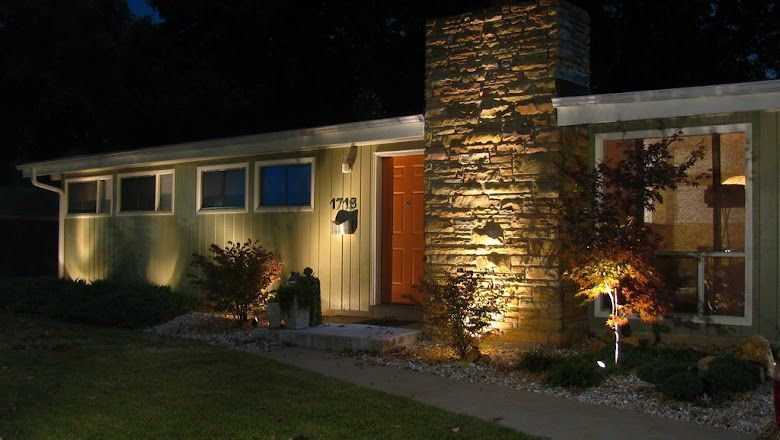 A house with a stone chimney is lit up at night.