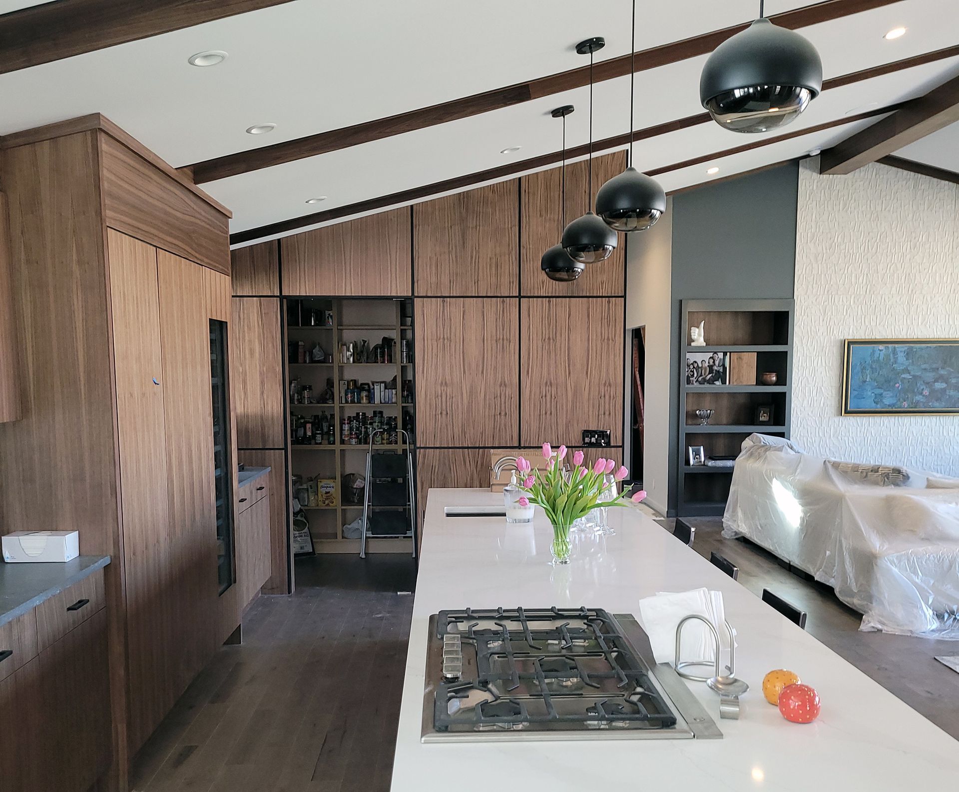 Modern kitchen with wood cabinetry, large island with cooktop, and hanging pendant lights.