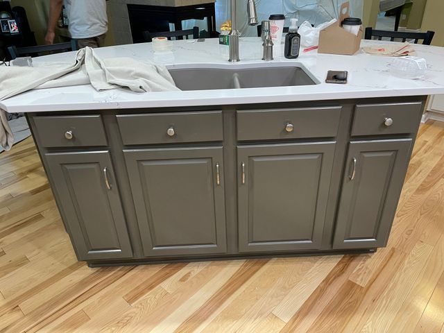 Gray kitchen island with sink and cabinets, on hardwood floors.