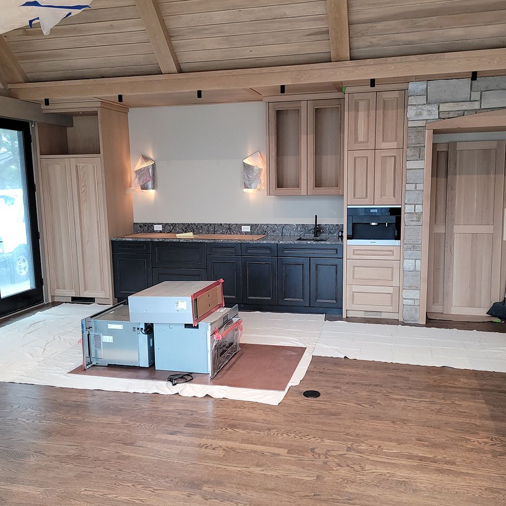 Interior with wooden cabinets, a built-in coffee maker, and appliances; light fixtures on a wall.