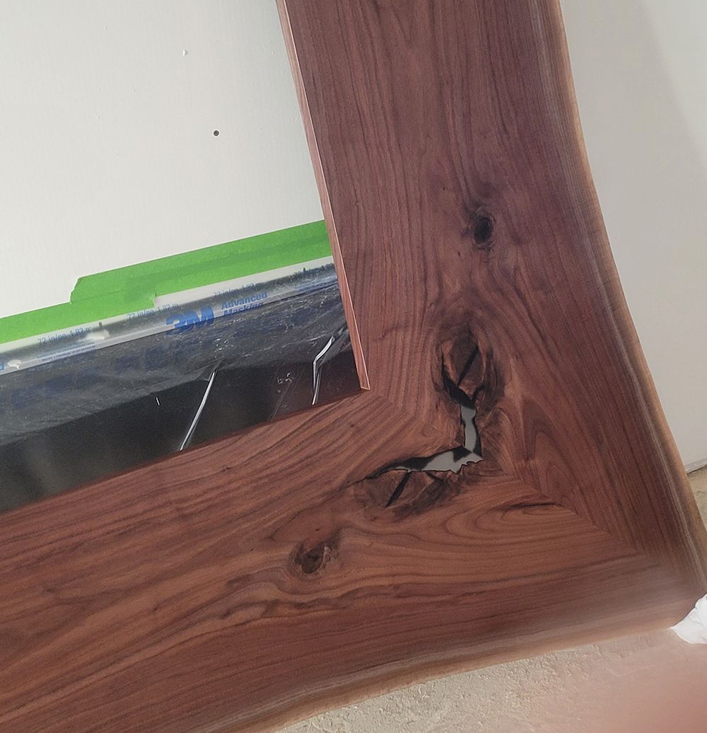 Wooden mirror frame with a natural wood grain and a knot.