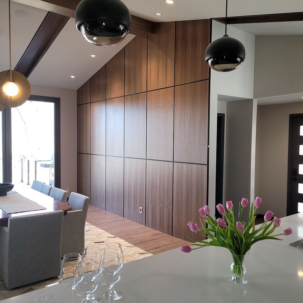 Dining room with wood paneled wall, modern lighting, table set for meal, and tulips in vase.