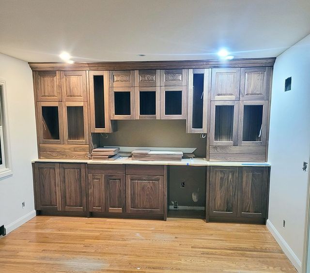 Wood cabinetry installed on a wall with open shelves and closed doors, with a wood floor.