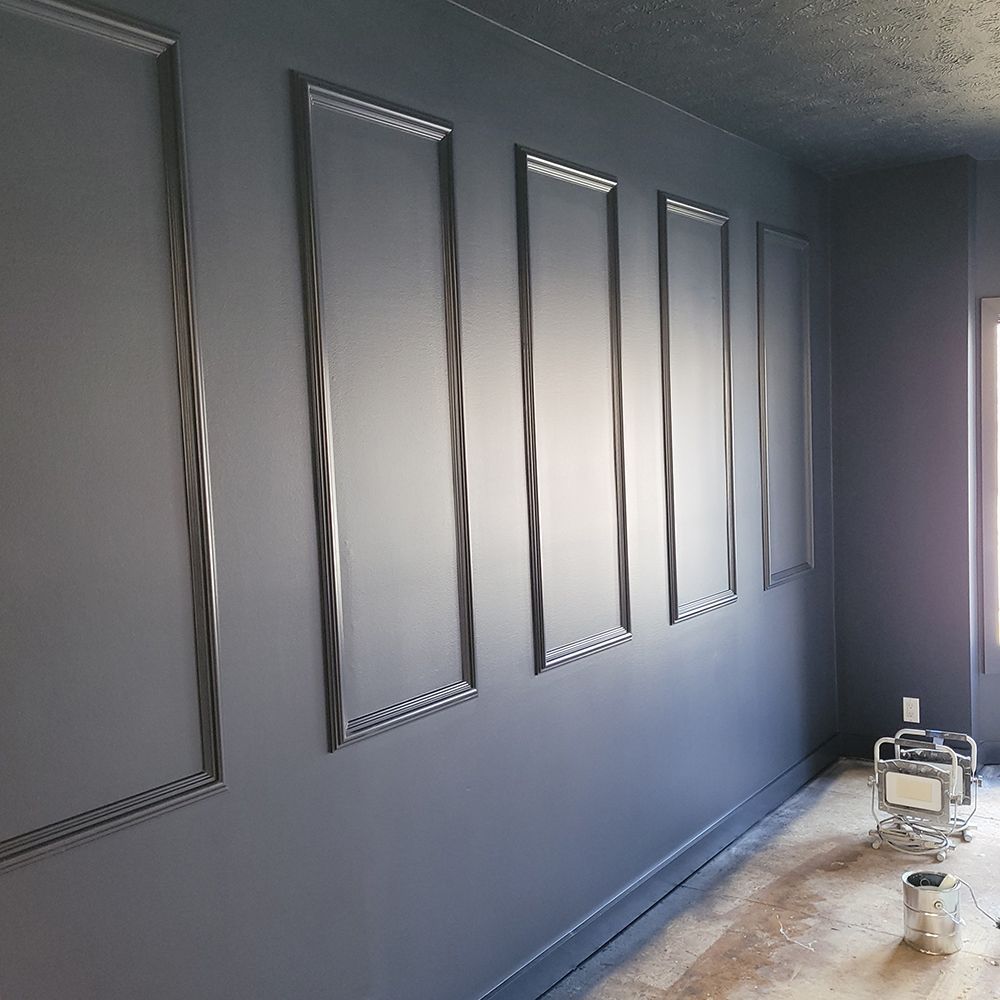 Dark gray wall with decorative rectangular frames, possibly being renovated.