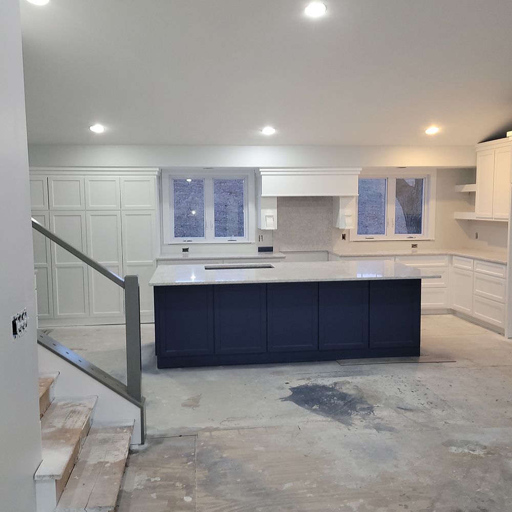 Newly constructed kitchen, featuring a blue island, white cabinets, and neutral walls.