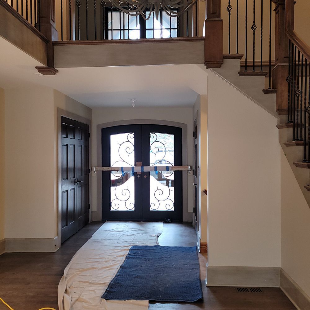 Entryway with double doors, stairs, dark wood door, light walls, and blue rug.