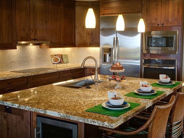 Kitchen with brown cabinets, granite countertops, stainless steel appliances, and a central island with seating.
