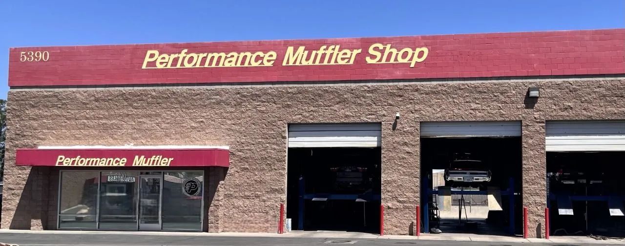 A brick automotive repair building with a maroon sign reading