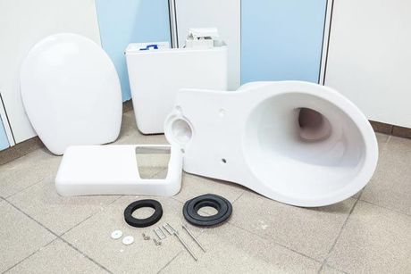 The parts of a toilet are laid out on the floor.