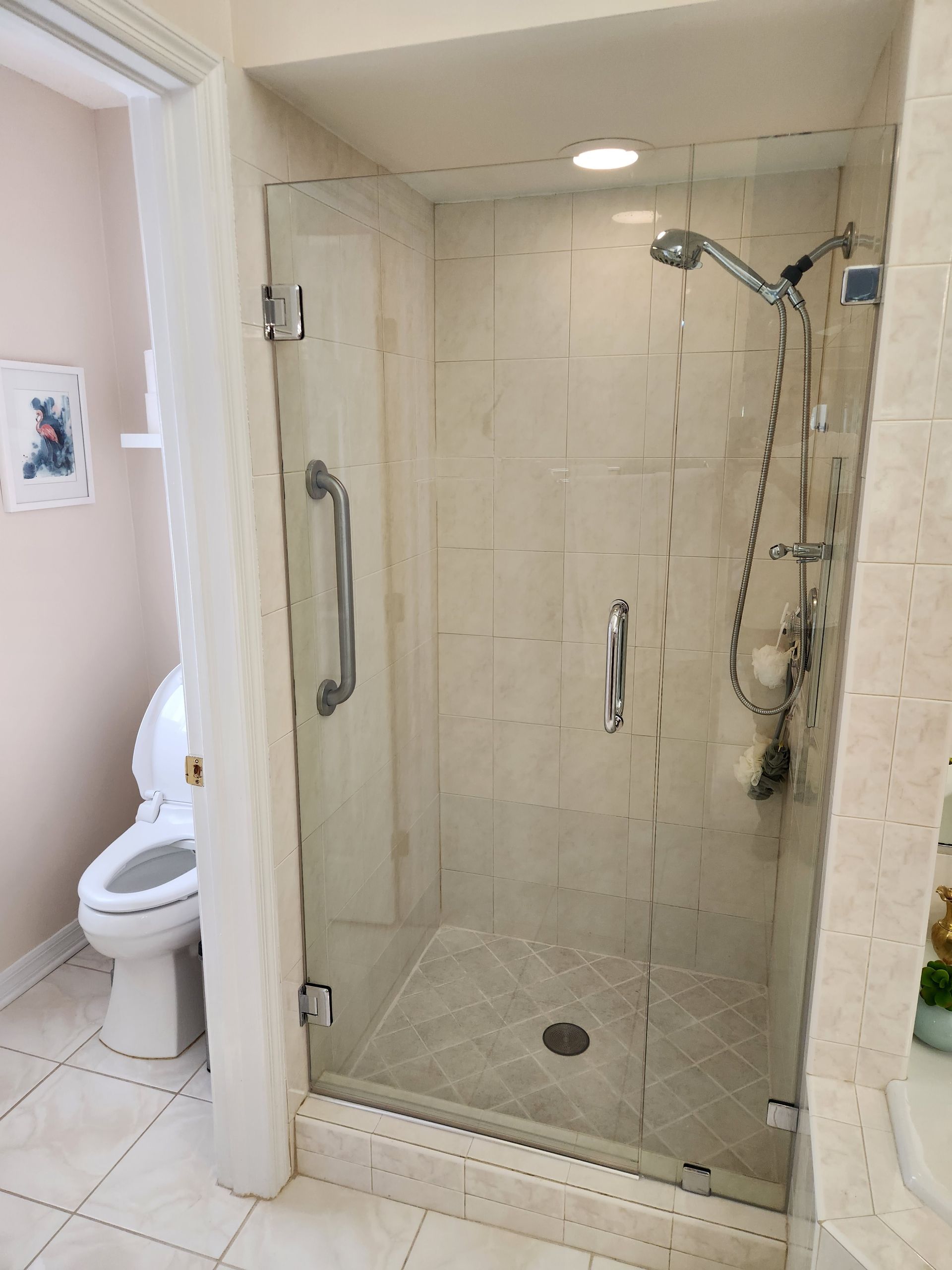 Bathroom with glass shower, toilet, and tiled walls.