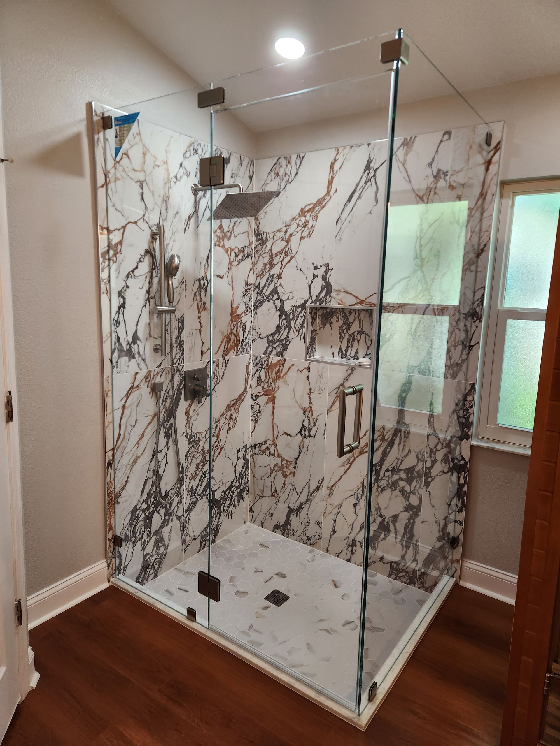 a bathroom with a walk in shower and marble walls .