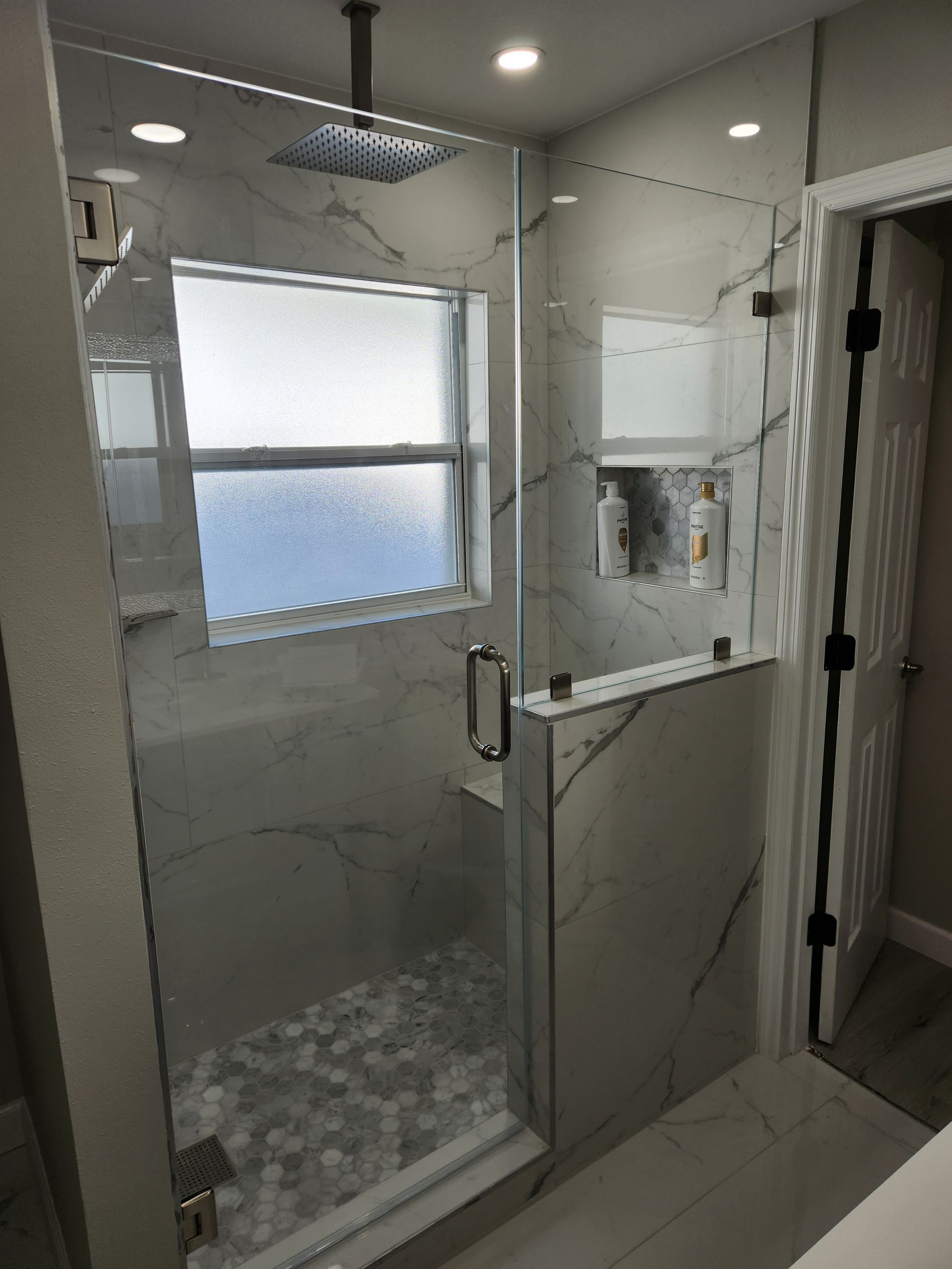 a bathroom with a walk in shower and a window .