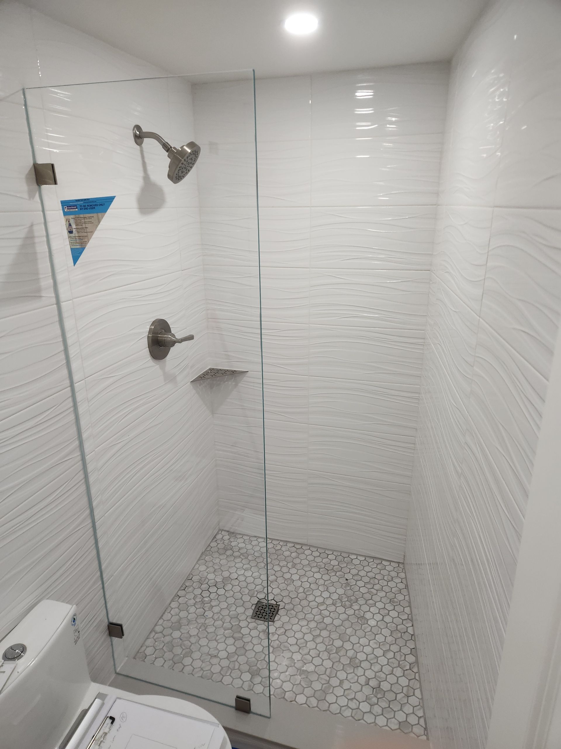 A bathroom with a walk in shower and a sink.