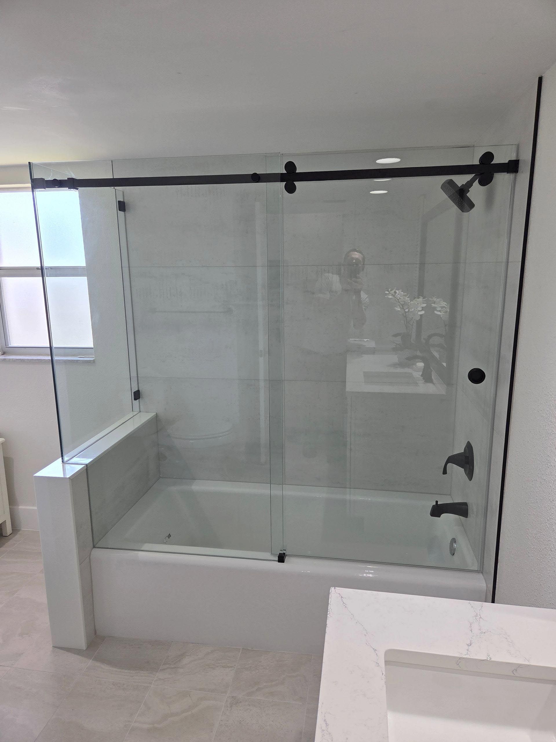 Modern bathroom with a glass walk-in shower, bathtub, and white tile walls
