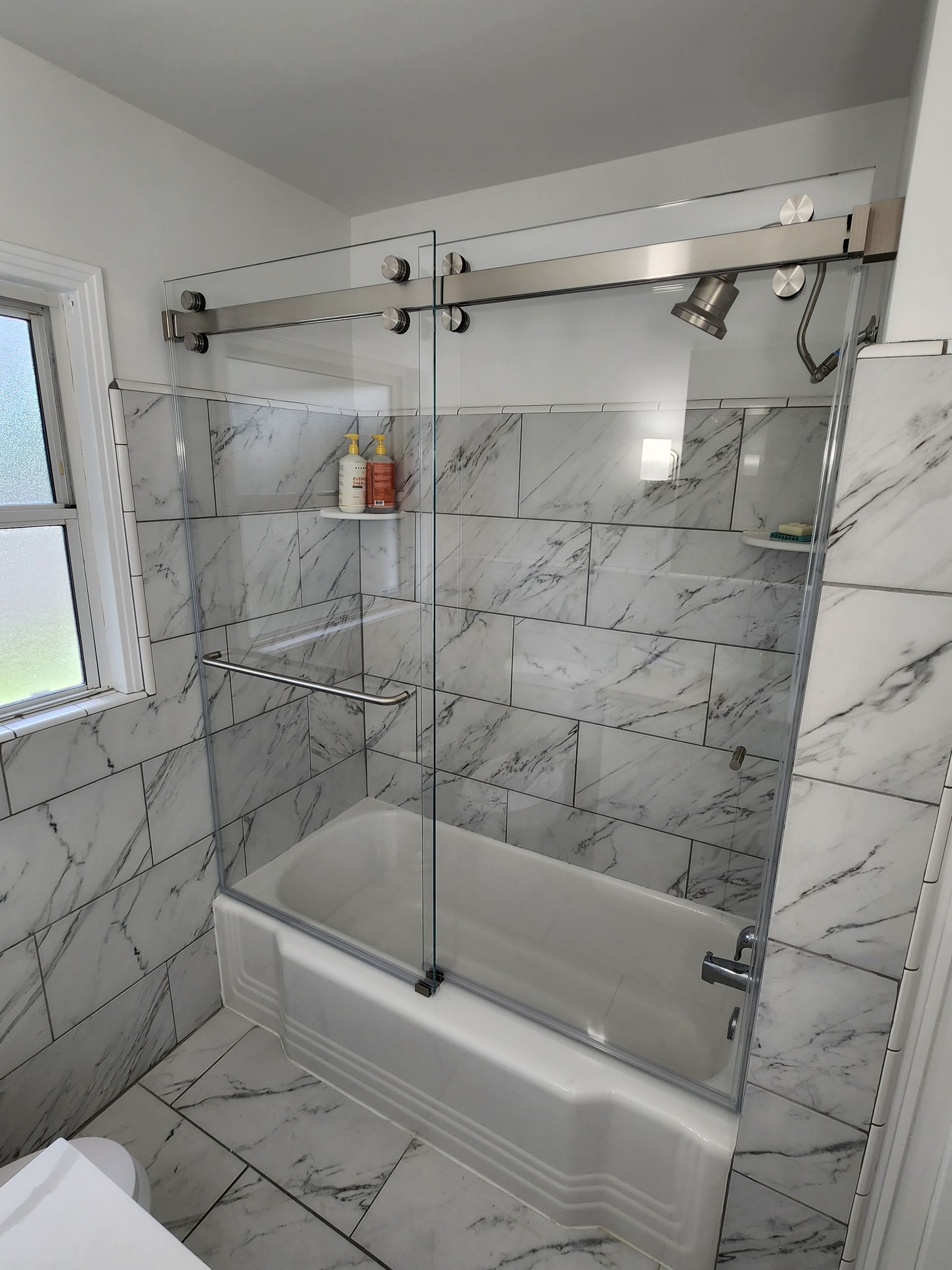 A bathroom with a bathtub and a sliding glass shower door.