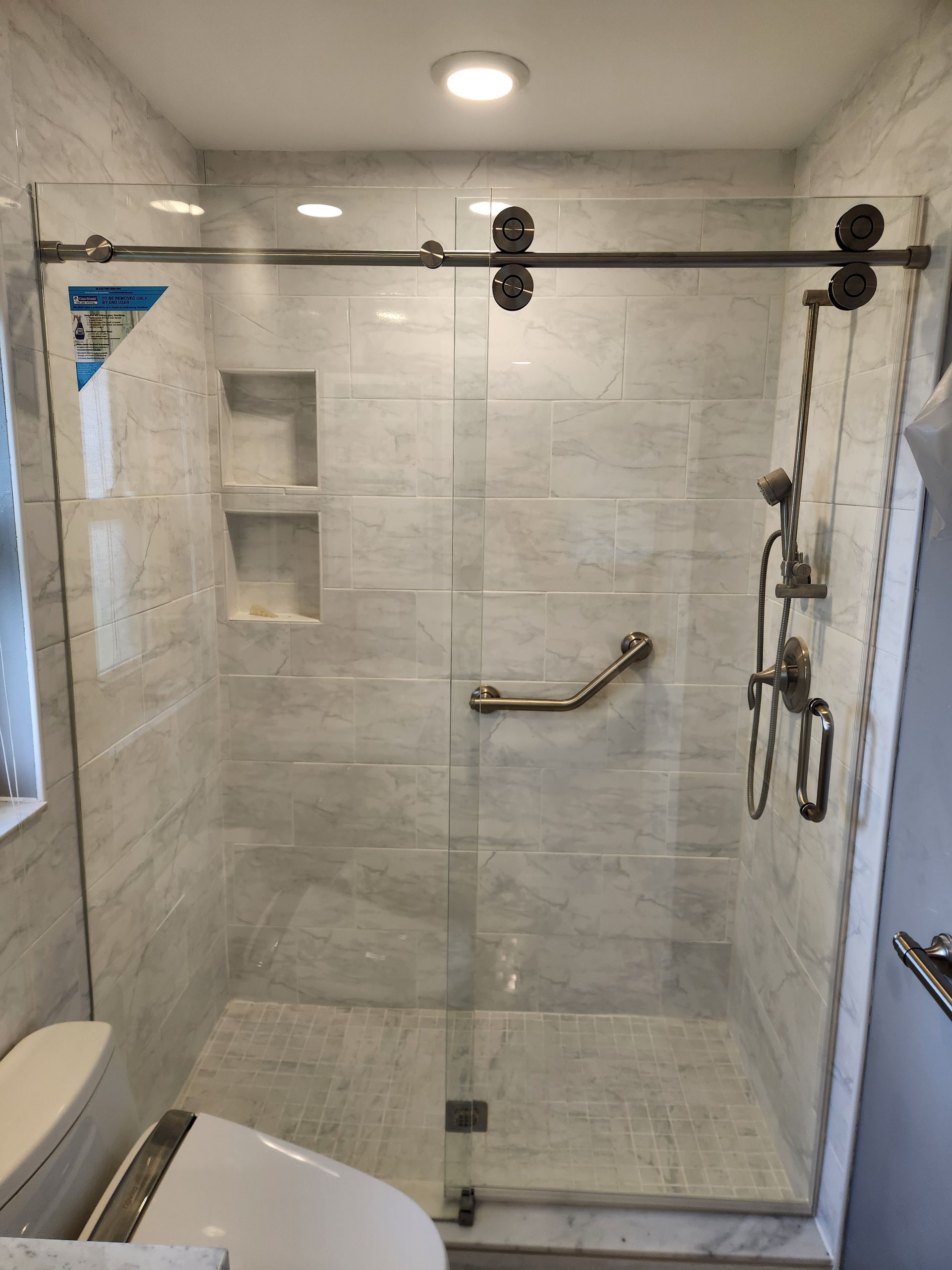 A bathroom with a sliding glass shower door and a toilet.