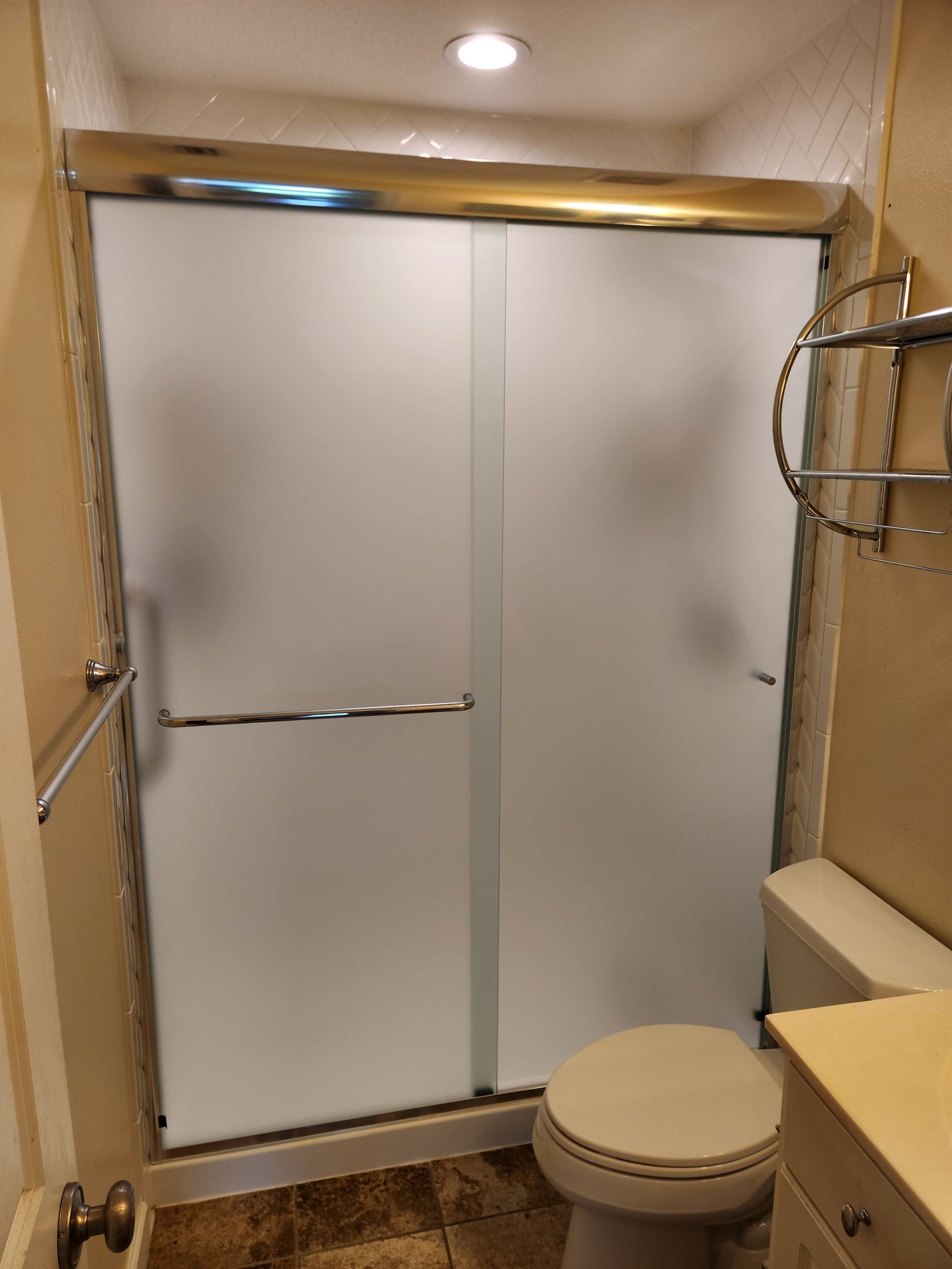 A bathroom with a toilet and a sliding glass shower door.