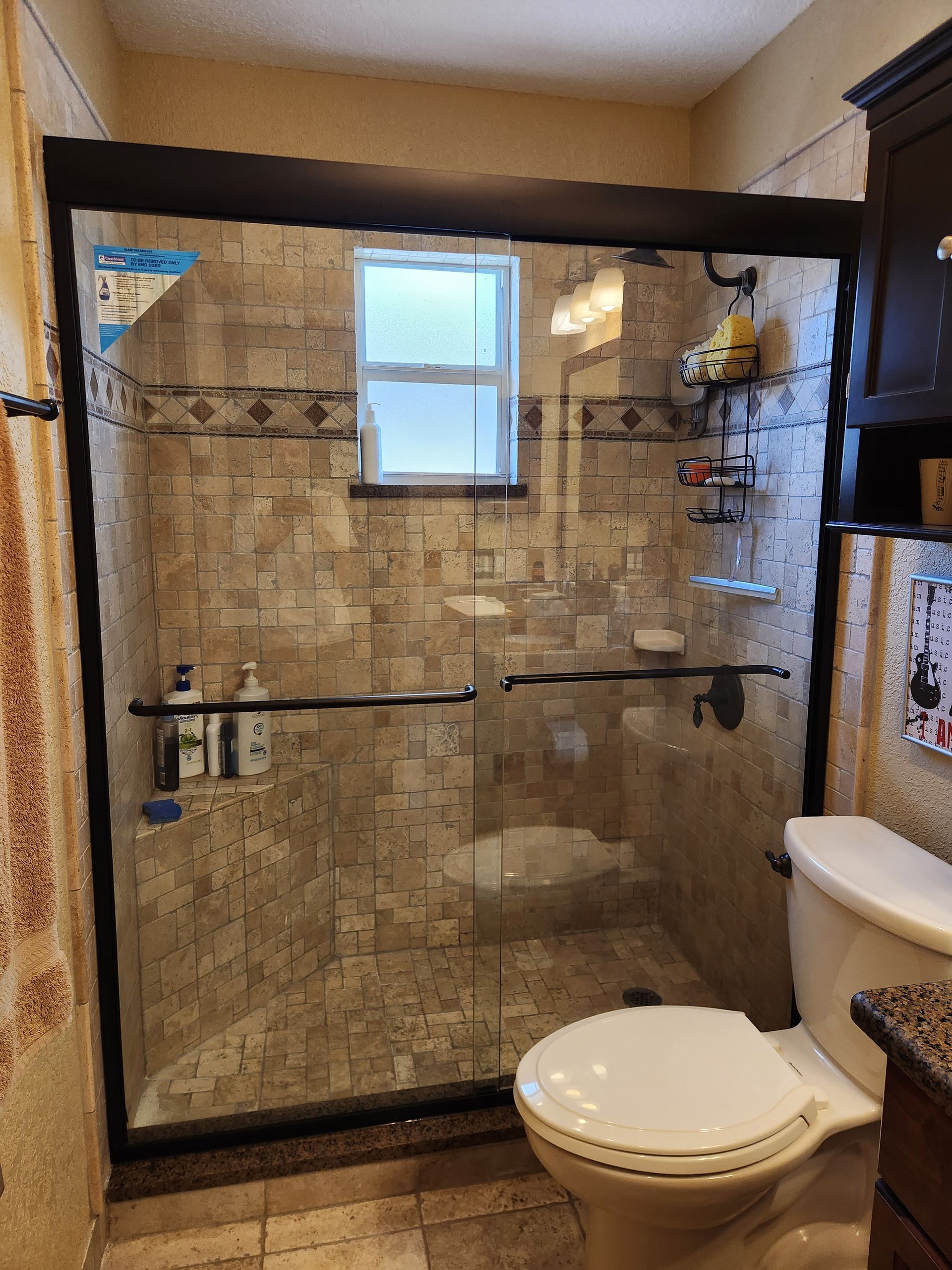 A bathroom with a toilet, shower, and window.