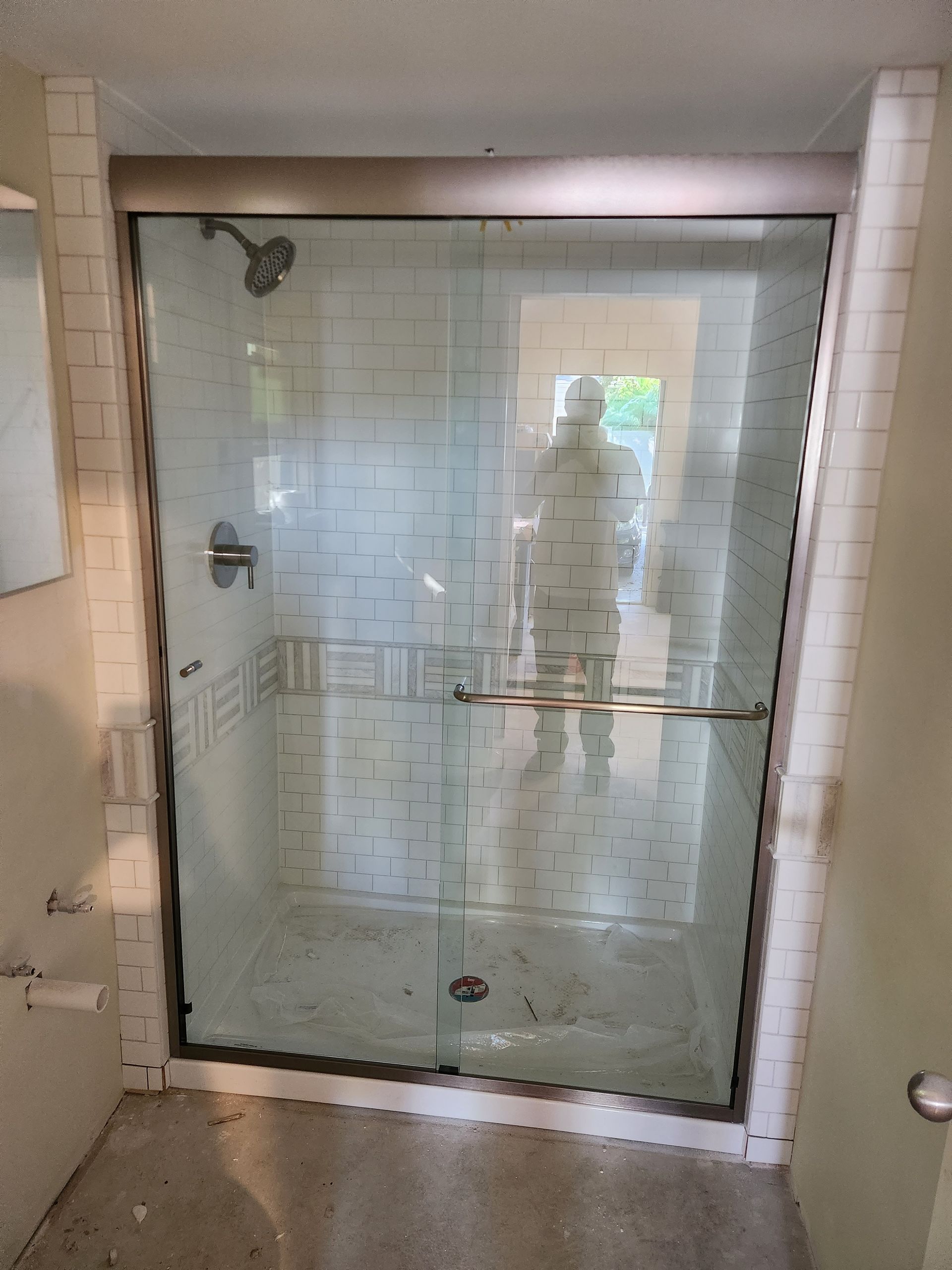 a bathroom with a sliding glass shower door and white tiles